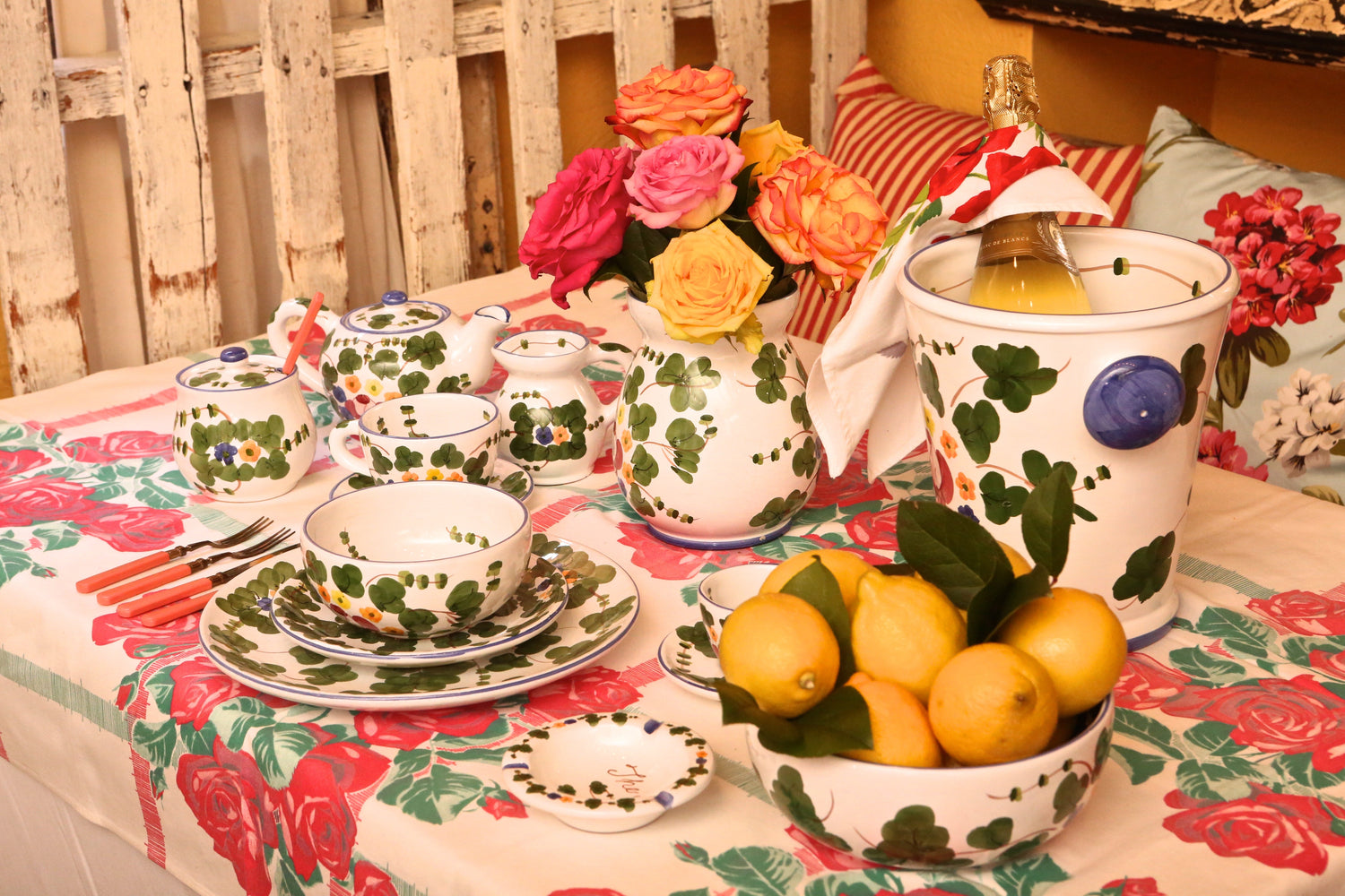 The Classic Ivy pattern table setting with green ivy and pink roses motifs on ceramic dinnerware, styled with roses and a floral tablecloth in a garden-inspired setting.